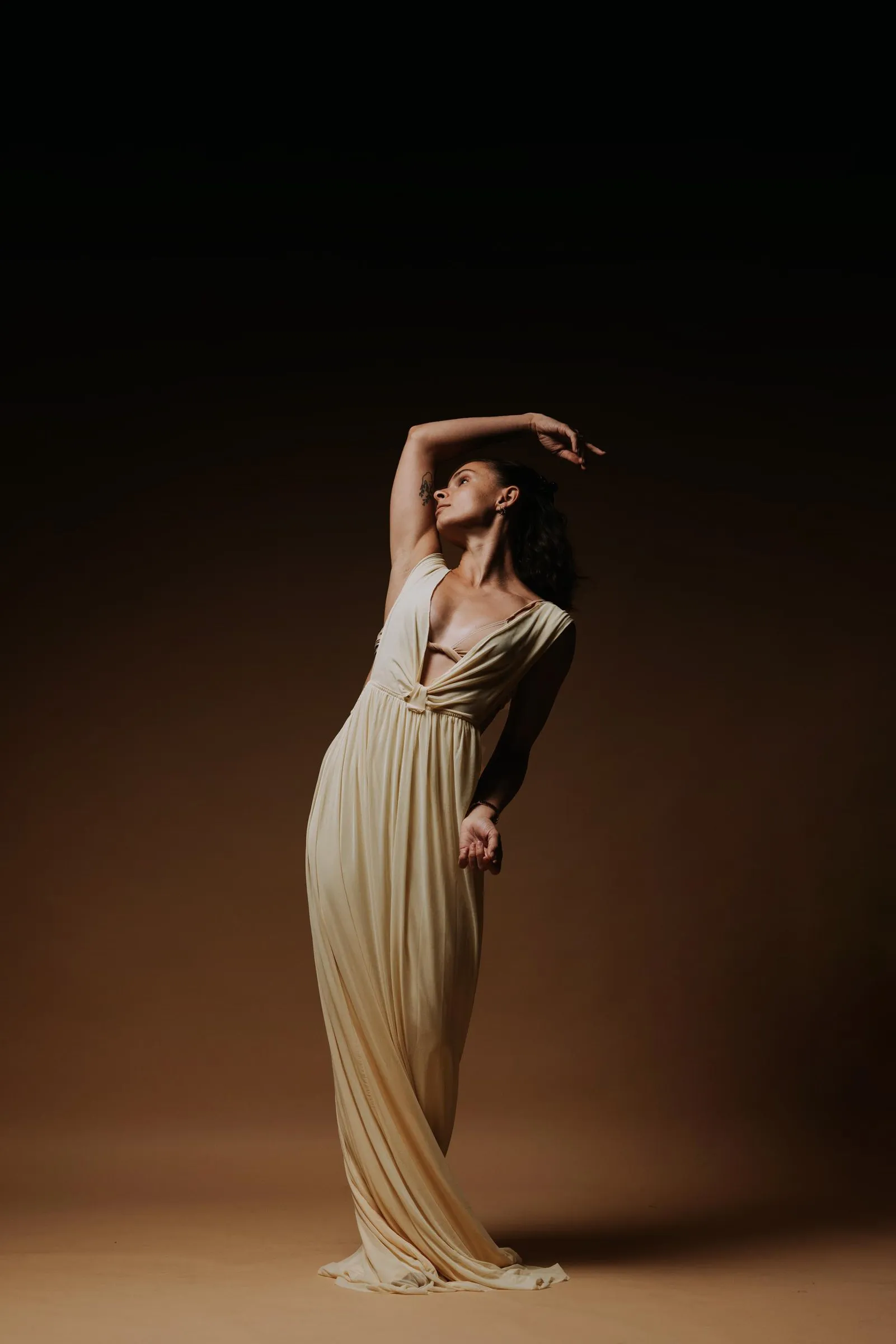 Paige Russell in a long cream gown, arms raised